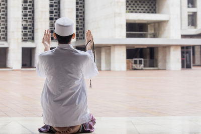 Rear view of man praying in mosque