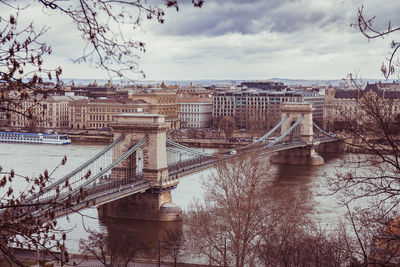 Bridge over river in city against sky