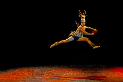 Midsection of man jumping against black background