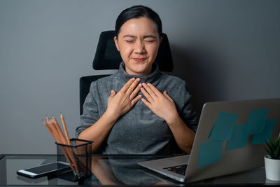 Young woman using mobile phone while sitting on table
