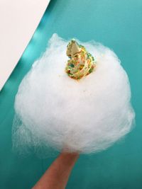 Close-up of hand holding ice cream over white background