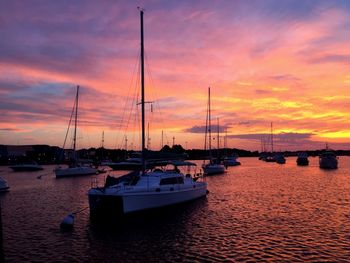 Boats sailing in sea against dramatic sky during sunset