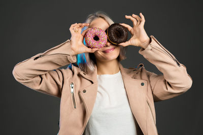 Portrait of a young woman holding camera over black background