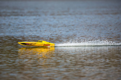 Yellow toy boat sailing in lake