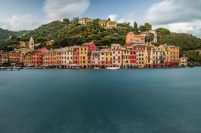 Buildings by river against sky