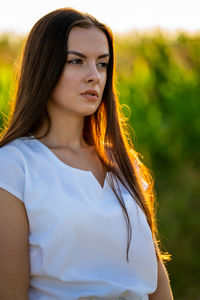 Portrait of young woman standing against trees