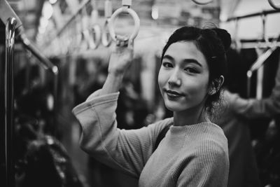 Portrait of beautiful young woman standing in subway train