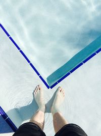 Low section of man standing by swimming pool