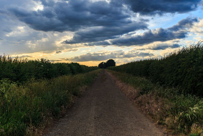 Dirt road along landscape and against sky