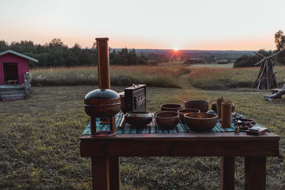 Tables and chairs on field against sky during sunset