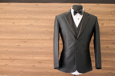 Close-up of suit on mannequin against wooden wall