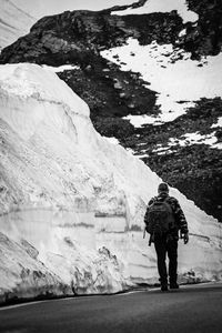 Rear view of person walking on snow covered mountain