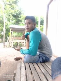 Young man looking away while sitting on seat