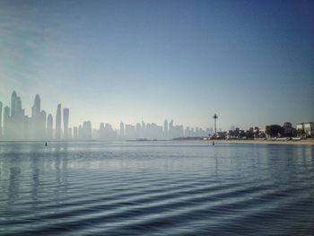 City at waterfront against clear sky