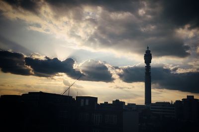 Low angle view of communications tower against cloudy sky