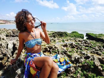 Young woman at beach against sky