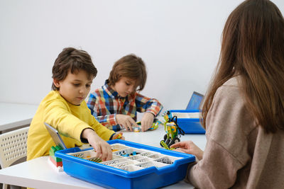 Students in school computer coding class building and learning to program robot vehicle. children