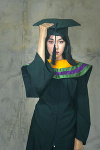 Portrait of young woman standing against wall