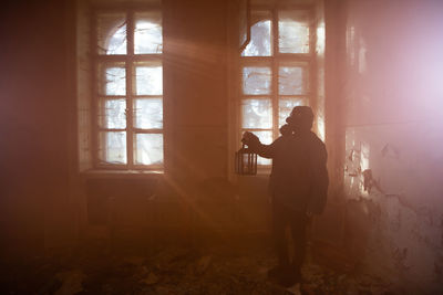 Man photographing through window in abandoned room