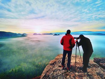 Rear view of man standing on mountain against sky