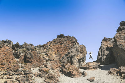 Man standing on rock against sky