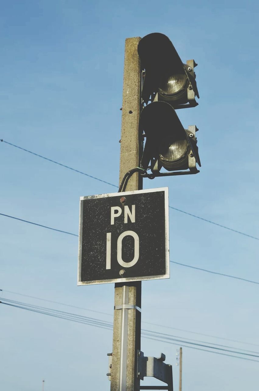 communication, text, western script, low angle view, guidance, information sign, sign, road sign, information, pole, number, directional sign, sky, arrow symbol, technology, capital letter, blue, power line, direction, connection