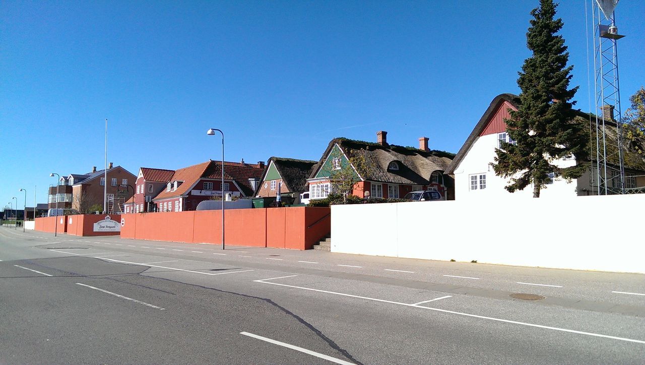 clear sky, blue, architecture, built structure, building exterior, copy space, road, street, house, transportation, sunlight, shadow, the way forward, residential structure, day, outdoors, road marking, no people, tree, city