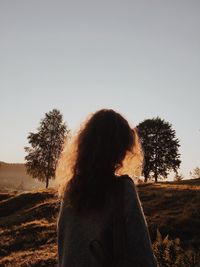 Rear view of woman standing on field against clear sky