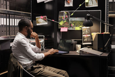 Side view of woman using mobile phone while sitting in office