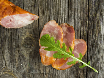 Directly above shot of sliced sausages with arugula on wooden table