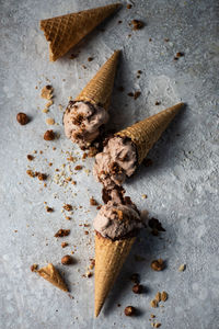 Top view on melted chocolate ice cream in waffle cones with nuts and on rustic concrete table