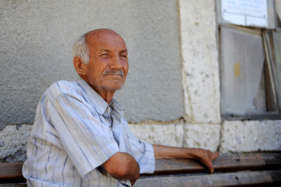 Portrait of man sitting against wall