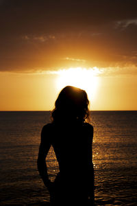 Silhouette woman looking at sea against sky during sunset