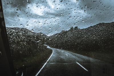 Road seen through wet window in rainy season