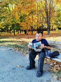 Full length of man sitting in park during autumn
