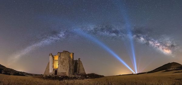 Low angle view of illuminated field against sky at night