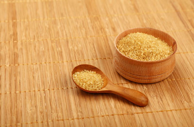 Close-up of brown sugar spoon and container on mat