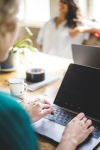 Creative professional using laptop at desk while coding in office