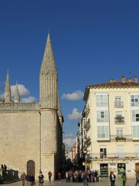 Tourists at town square against blue sky