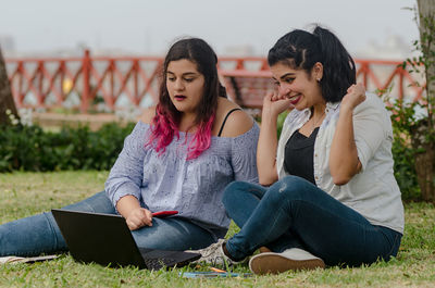 Cheerful friends using technology at park