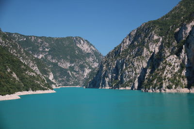 Scenic view of sea and mountains against clear blue sky