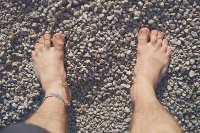 Low section of woman legs on pebbles at beach