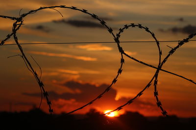 Close-up of silhouette fence against orange sky