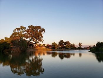 Scenic view of lake against clear sky at sunset