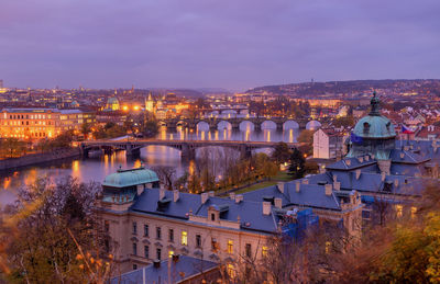 High angle view of bridges over river in illuminated city at dusk