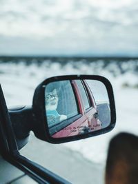 Close-up of reflection on side-view mirror against sky