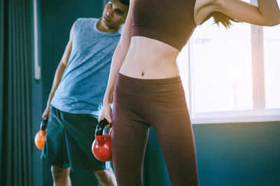 Midsection of young woman standing against wall