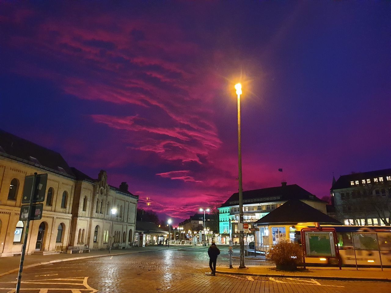 ILLUMINATED STREET AMIDST BUILDINGS AT NIGHT