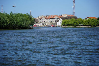 Buildings by river against sky in city