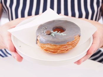 Close-up of hand holding donut on plate
